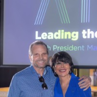 GVSU President smiles at camera with a man in front of the Leading the Way to Atlanta presentation